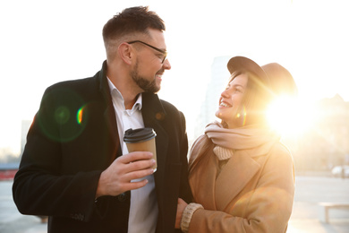 Photo of Lovely couple with cup of coffee on city street in morning