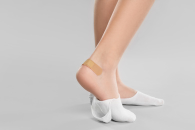Photo of Girl showing foot with sticking plaster on light grey background, closeup