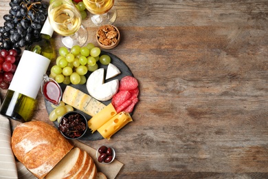 Photo of Flat lay composition with wine, snacks and space for text on wooden background