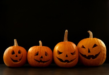 Spooky Jack pumpkin head lanterns on grey table against black background, space for text. Halloween decoration