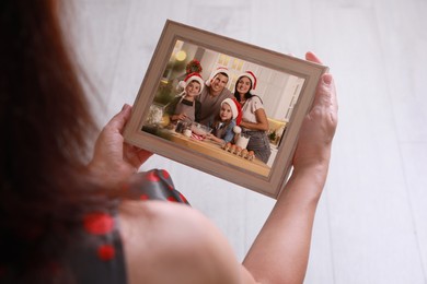 Image of Woman holding frame with photo portrait of her family indoors, closeup