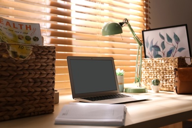 Comfortable workplace with laptop near window at home