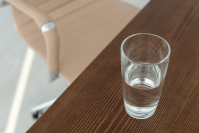 Photo of Glass of water on table in office. Space for text