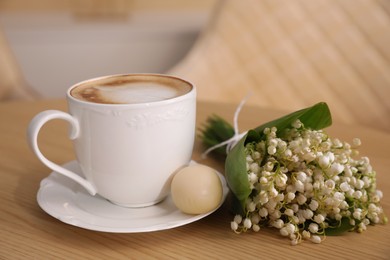 Cup of aromatic morning coffee and flowers on wooden table in cafe