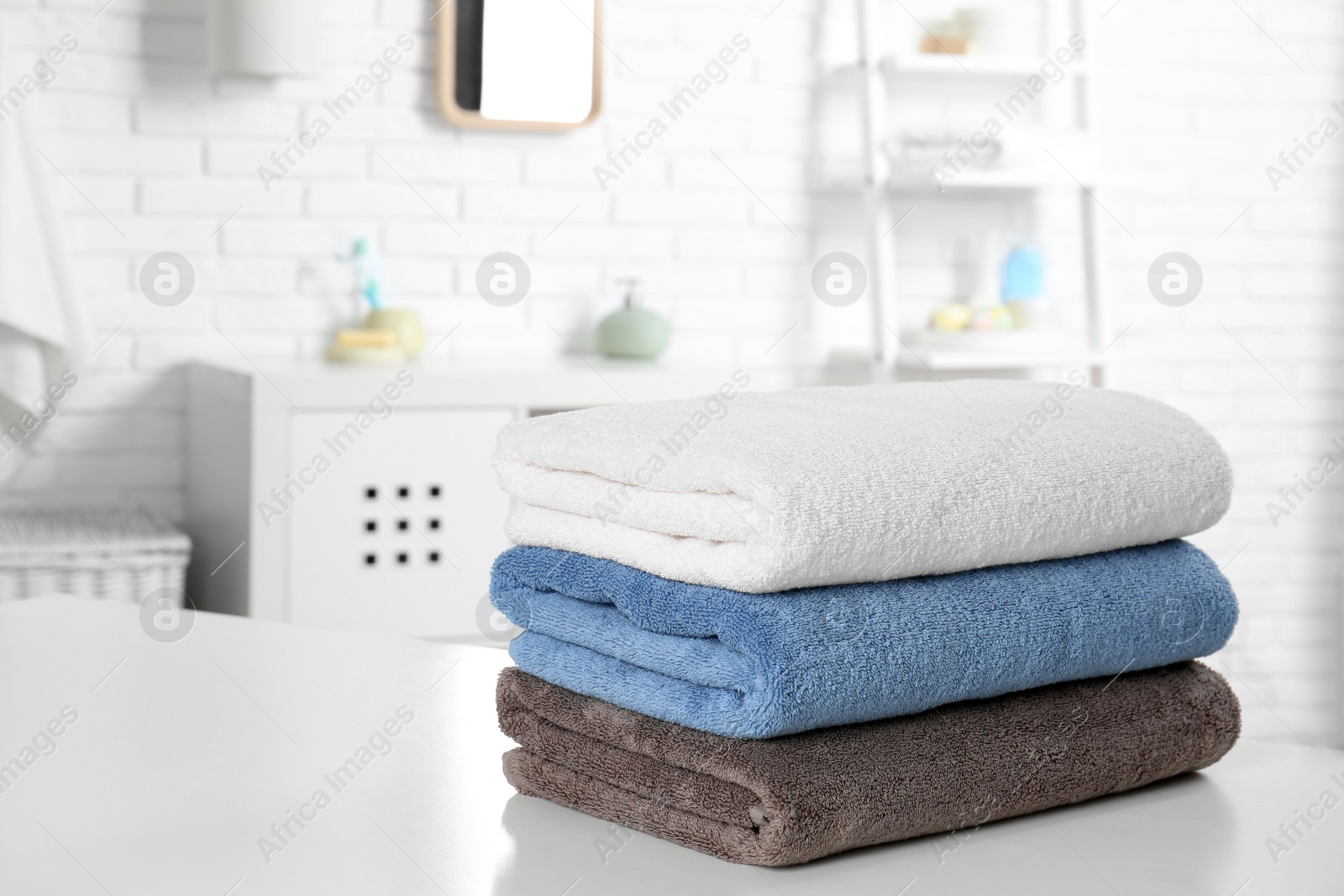 Photo of Stack of fresh towels on table in bathroom. Space for text