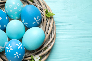 Photo of Nest with Easter eggs on light blue wooden background, top view. Space for text