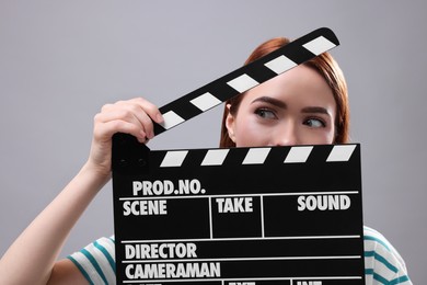 Photo of Emotional actress with clapperboard on grey background. Film industry
