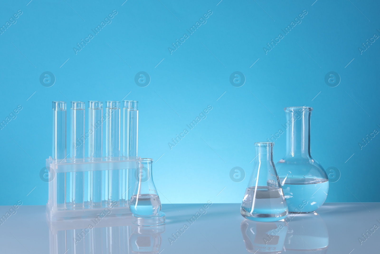 Photo of Laboratory analysis. Glass test tubes and flasks on table against light blue background