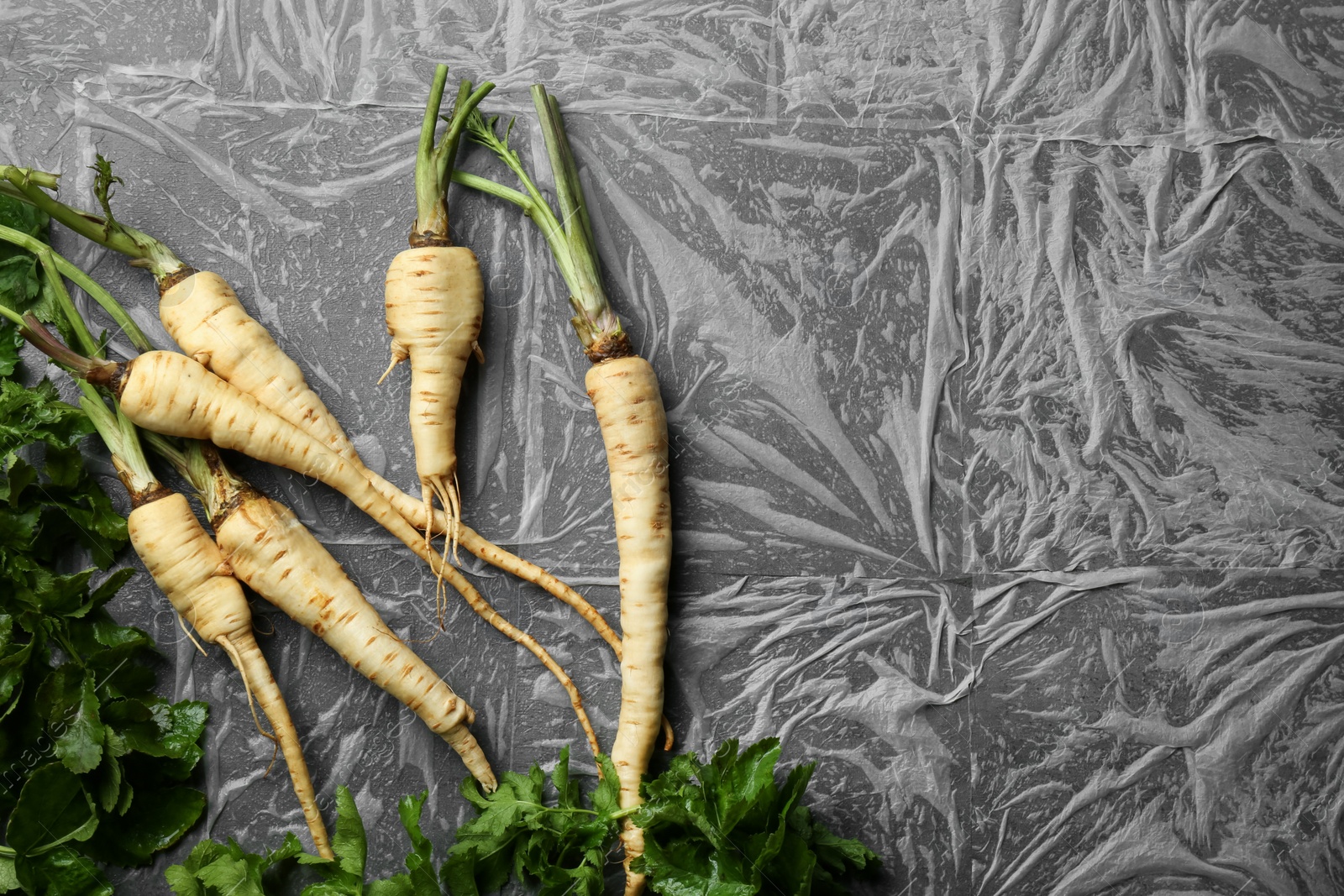 Photo of Delicious fresh ripe parsnips on grey table, flat lay. Space for text