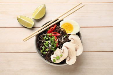 Photo of Tasty buckwheat noodles (soba) with mushrooms, egg and chili pepper served on wooden table, flat lay