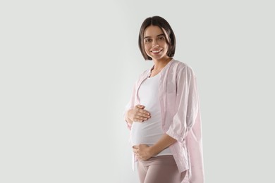 Happy young pregnant woman on white background, space for text