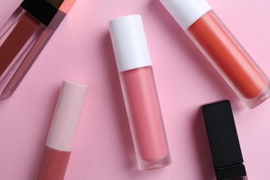 Photo of Different lip glosses on pink background, flat lay