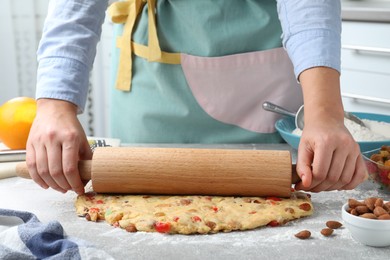 Woman rolling dough for Stollen at grey table, closeup. Baking traditional German Christmas bread