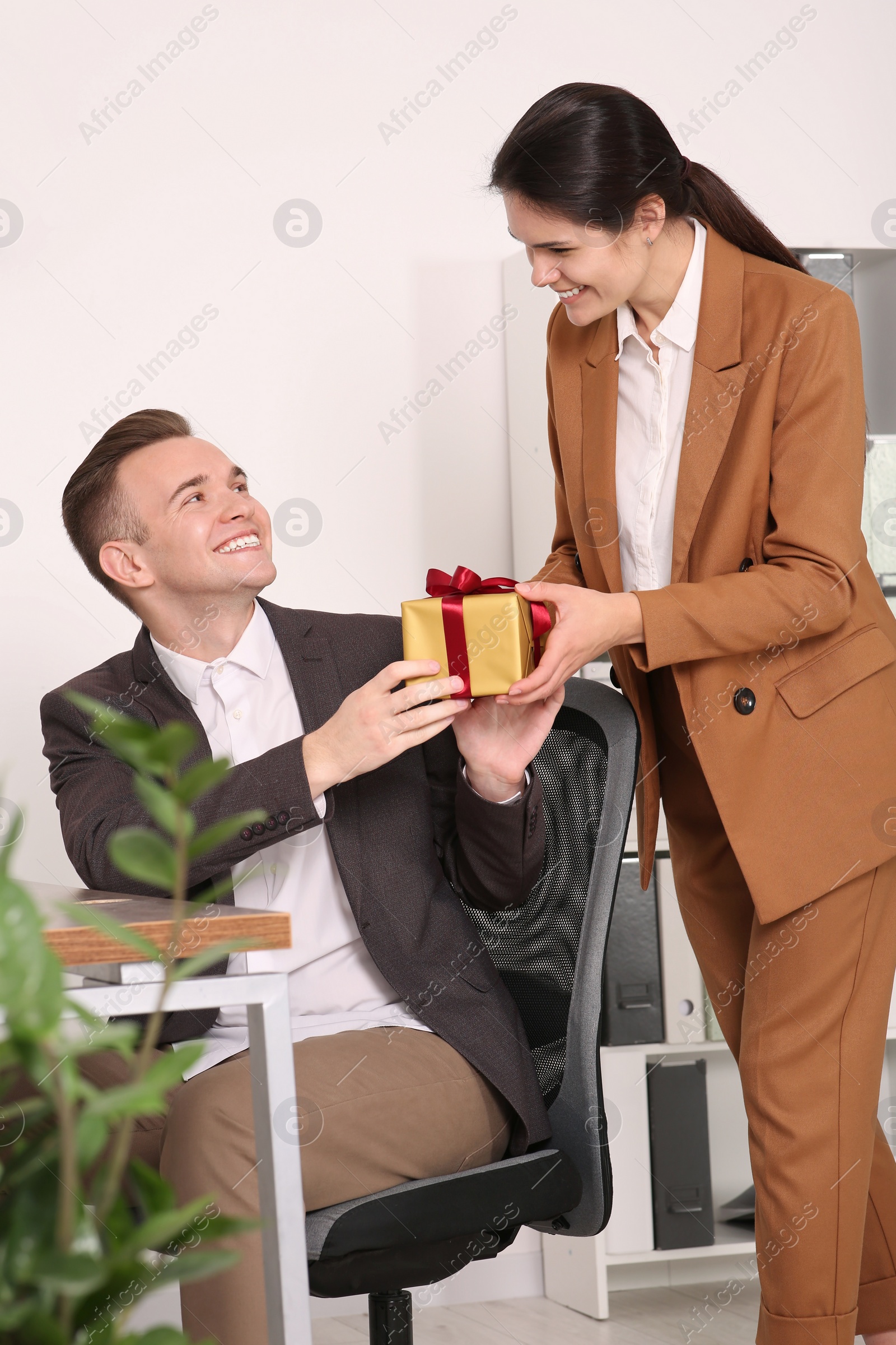 Photo of Woman presenting gift to her colleague in office