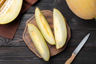 Photo of Pieces of delicious honeydew melon on black wooden table, flat lay