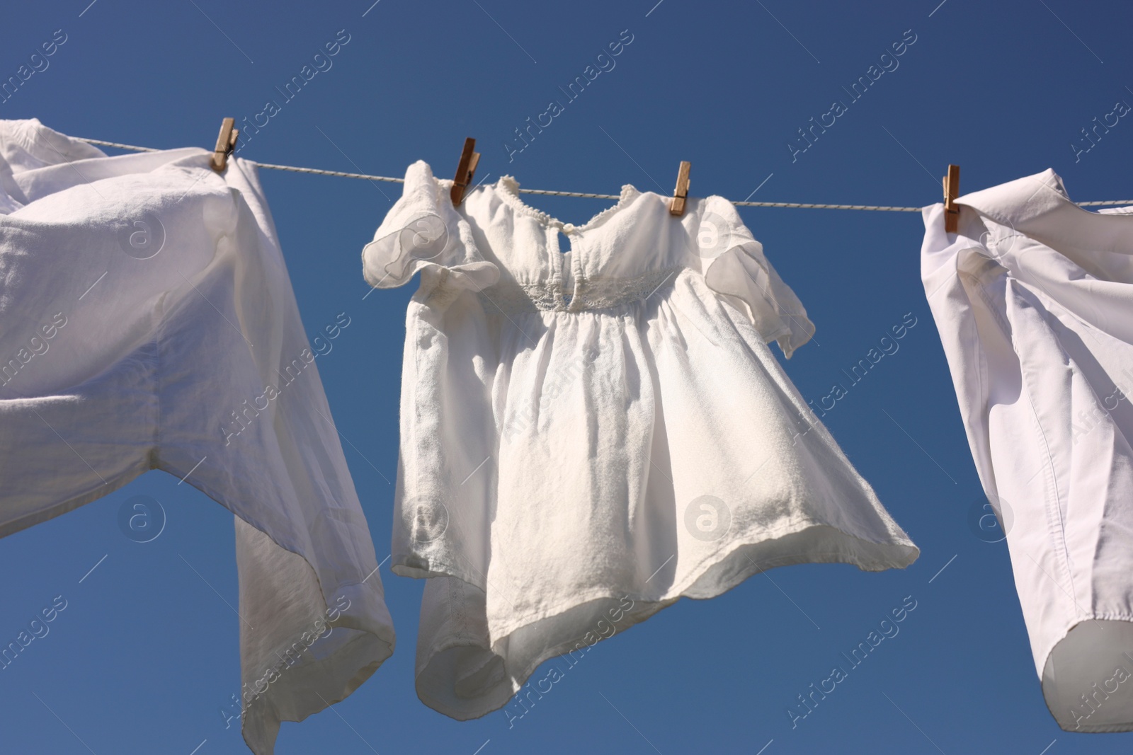 Photo of Clean clothes hanging on washing line against sky, low angle view. Drying laundry