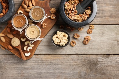 Photo of Making nut butters from different nuts. Flat lay composition with space for text on wooden table