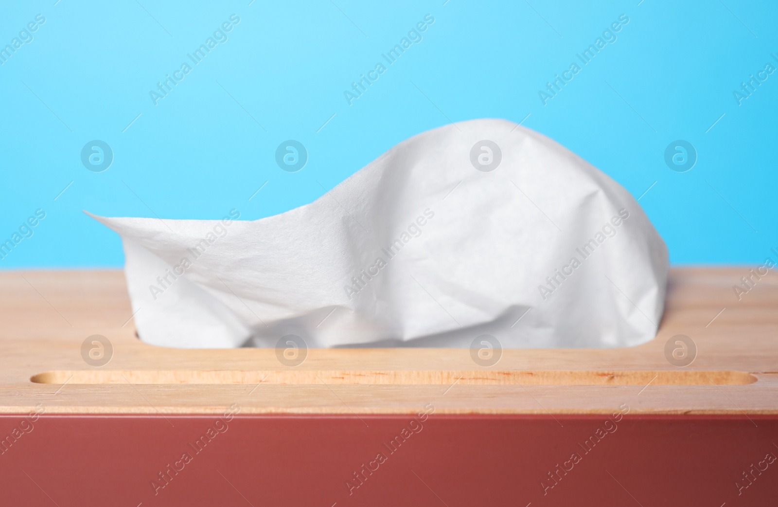 Photo of Holder with paper tissues on light blue background, closeup