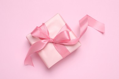 Photo of Beautiful gift box with bow on pink background, top view