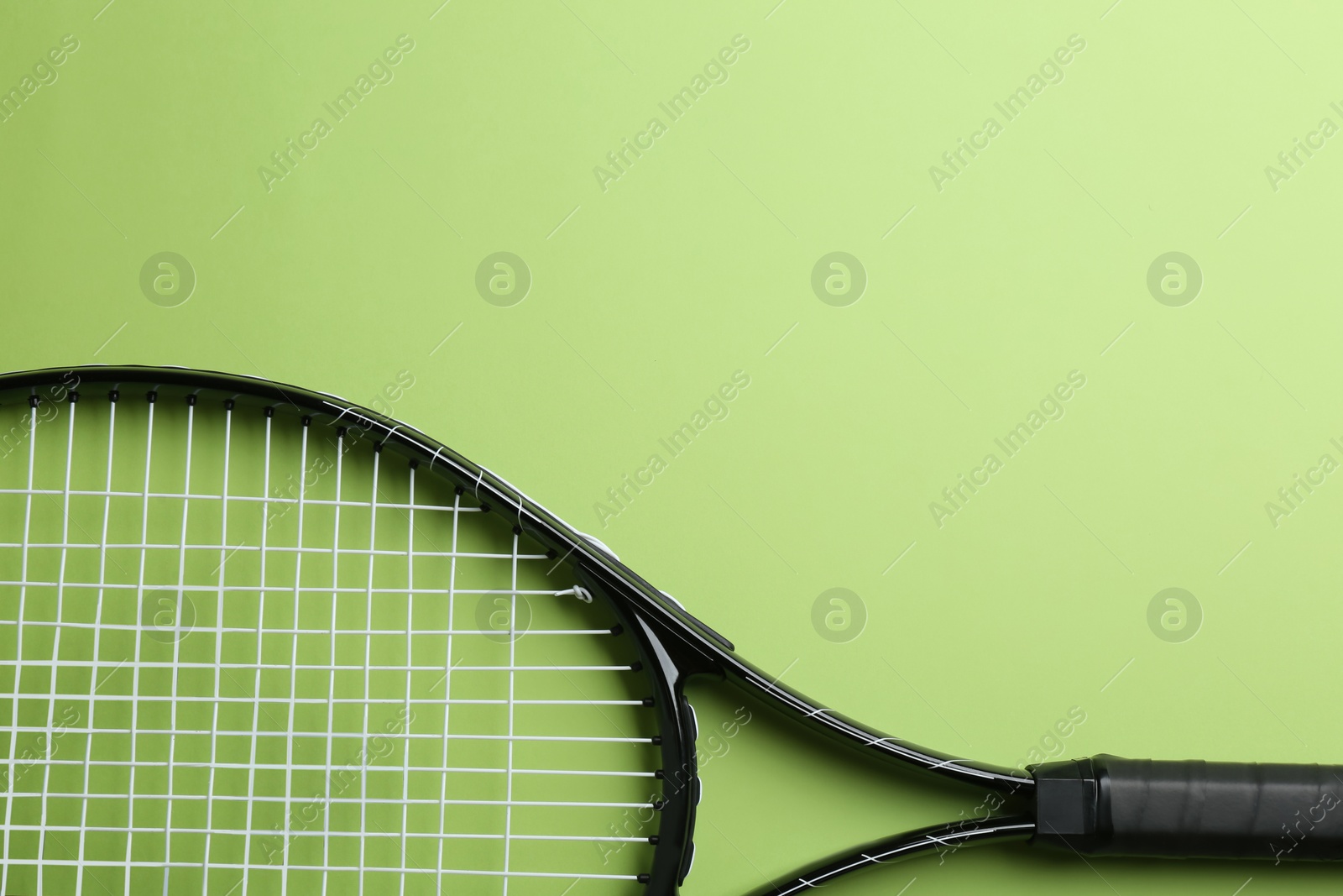 Photo of Tennis racket on green background, top view. Space for text
