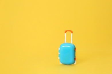 Stylish child blue suitcase on yellow background, space for text