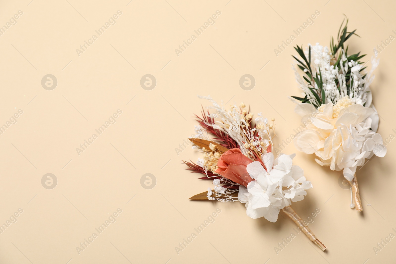 Photo of Stylish boutonnieres on beige background, top view. Space for text