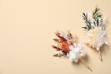 Stylish boutonnieres on beige background, top view. Space for text