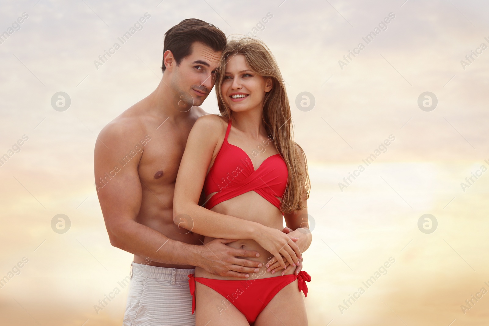 Photo of Happy young couple spending time together on sea beach at sunset