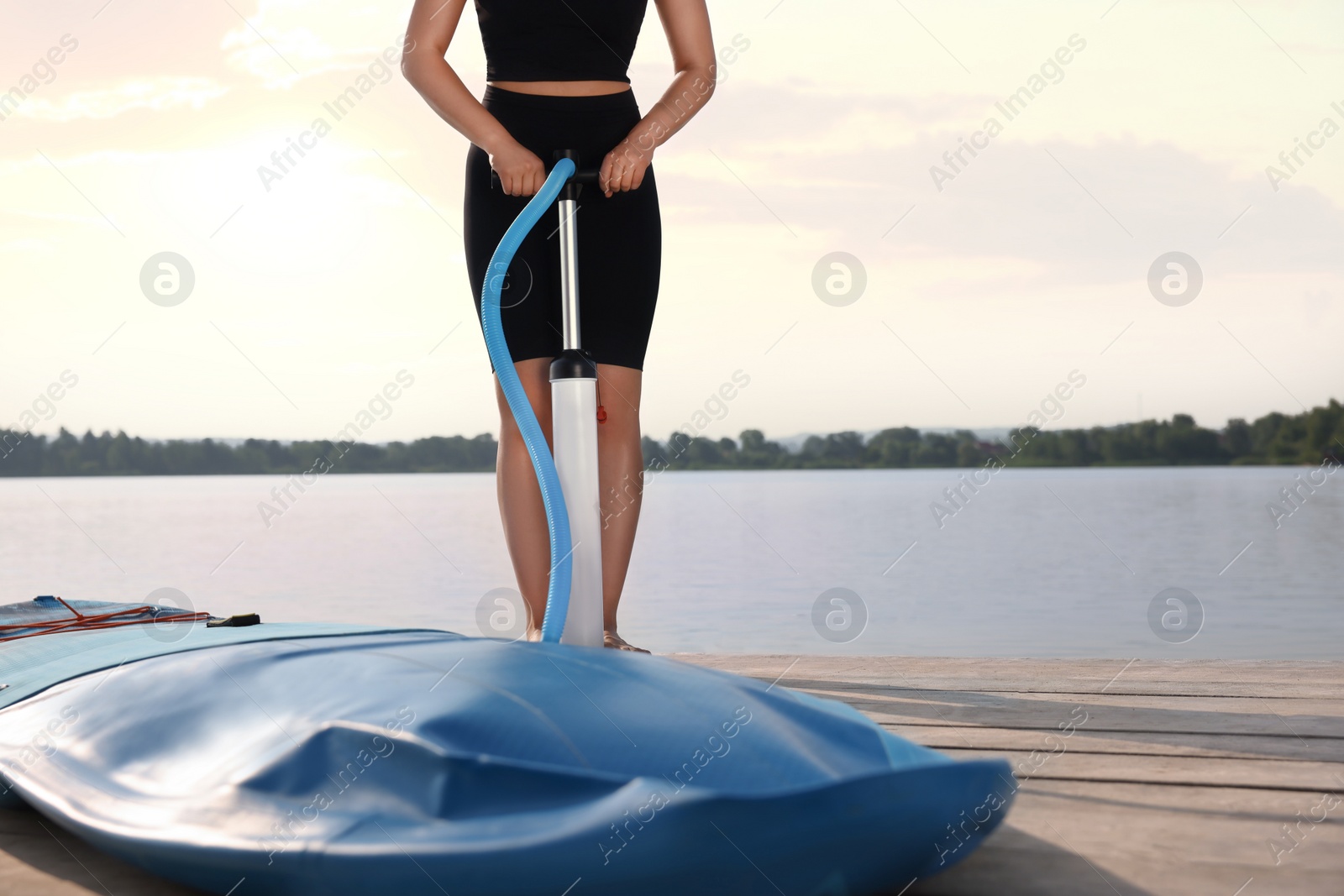 Photo of Woman pumping up SUP board on pier, closeup. Space for text