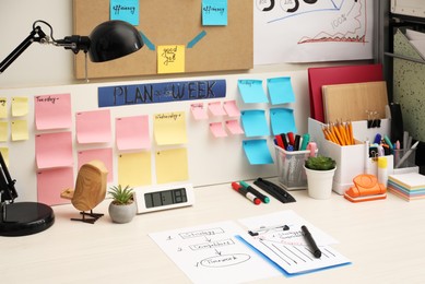 Business process planning and optimization. Workplace with lamp, colorful paper notes and other stationery on white wooden table