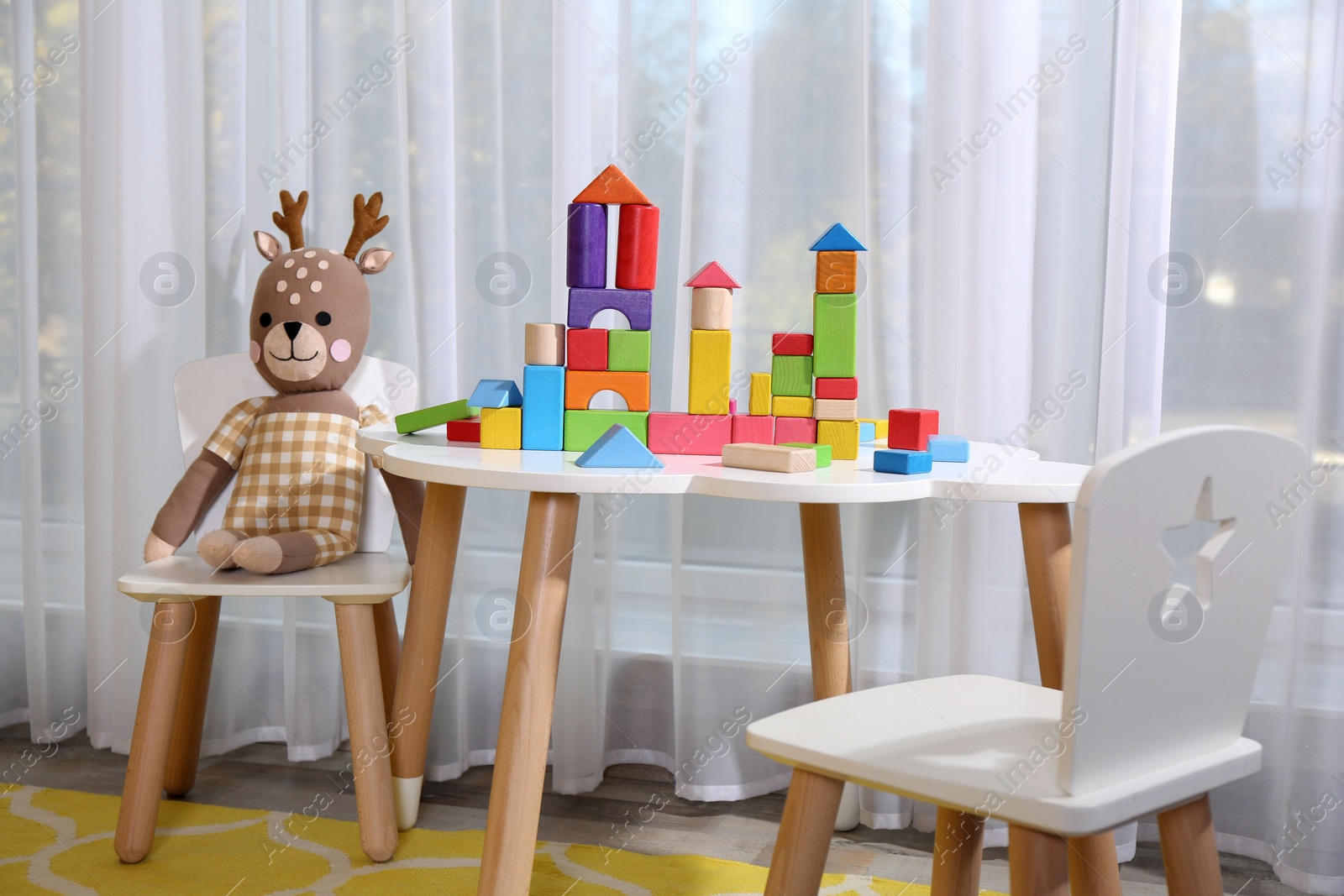 Photo of Toy deer near white table with colorful building blocks in playroom