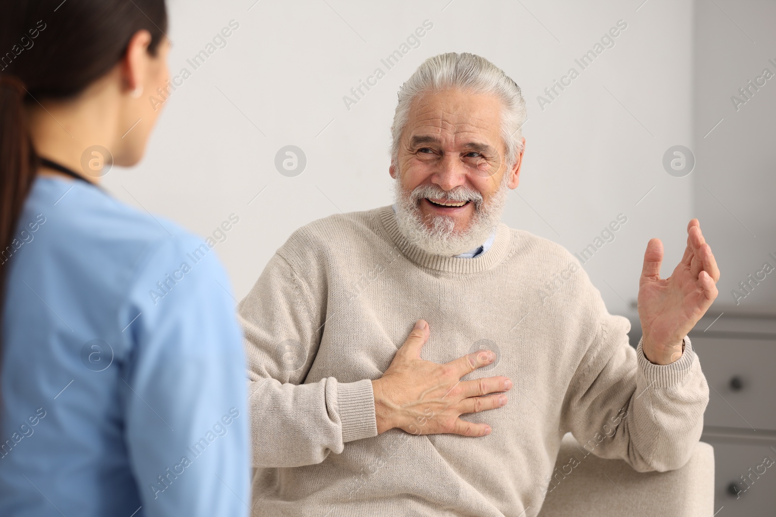 Photo of Smiling elderly patient laughing with nurse in hospital