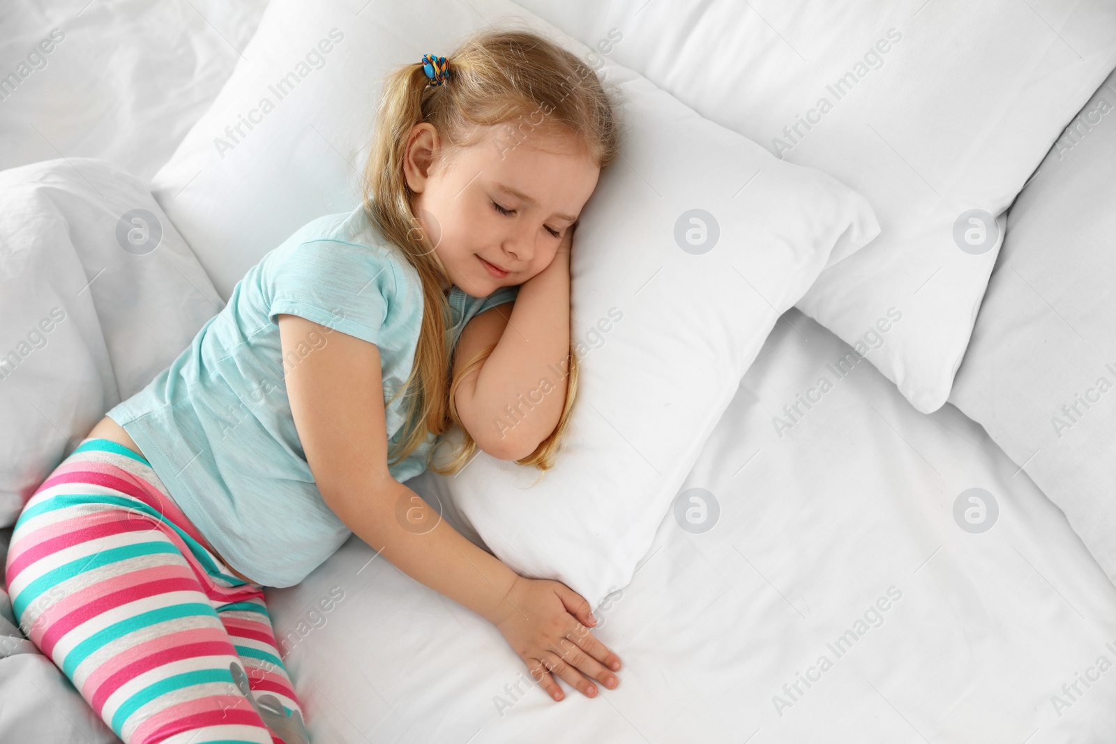 Photo of Portrait of cute little girl sleeping in large bed, above view