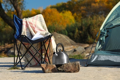 Photo of Chair and metal kettle near camping tent outdoors