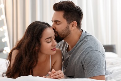 Photo of Man kissing his girlfriend on bed indoors