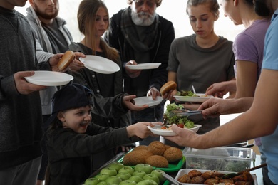 Photo of Poor people receiving food from volunteers indoors
