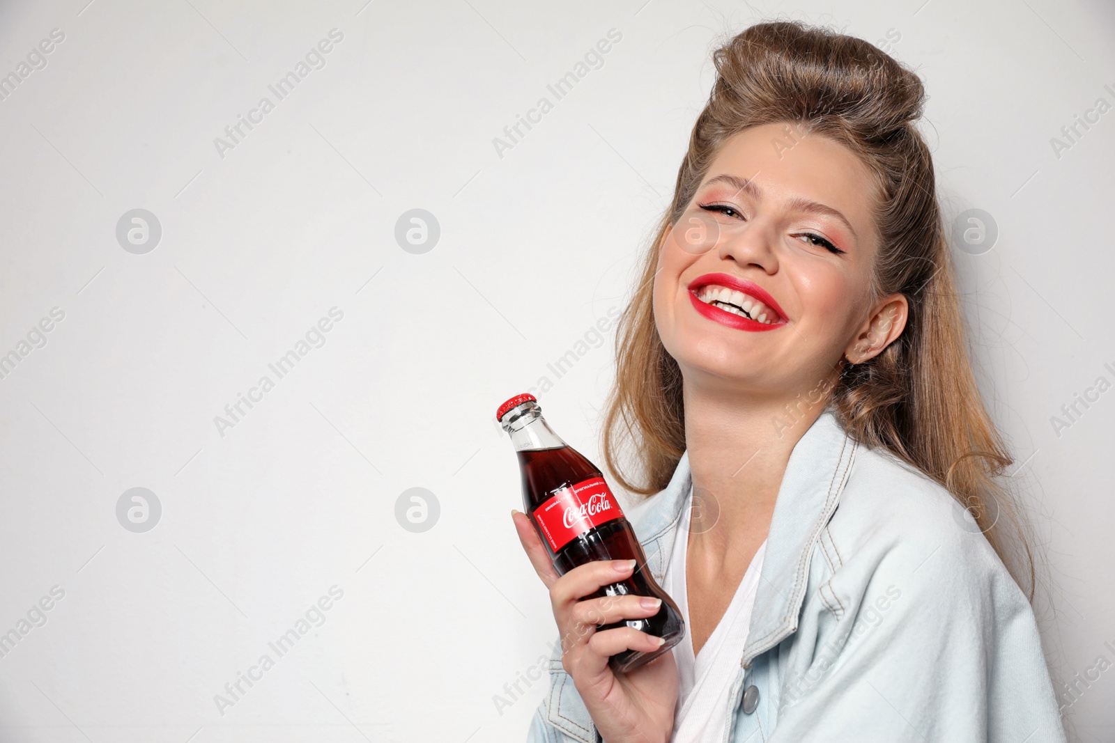 Photo of MYKOLAIV, UKRAINE - NOVEMBER 28, 2018: Young woman with bottle of Coca-Cola on white background, space for text