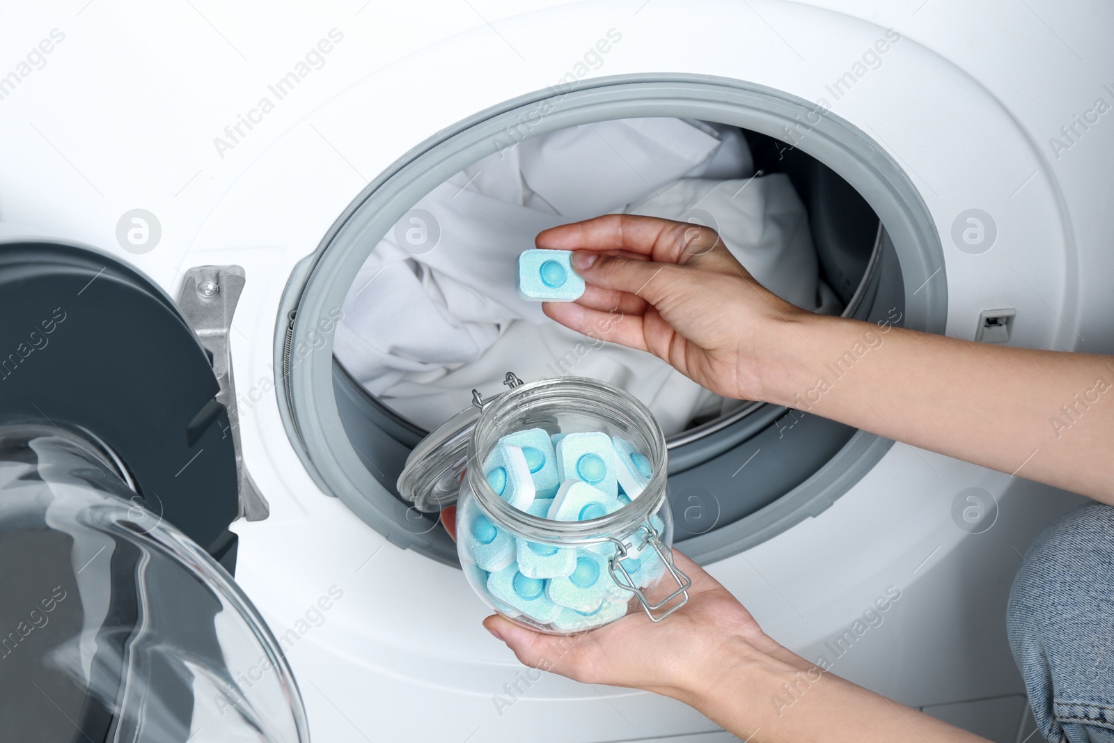 Photo of Woman putting water softener tablet into washing machine, closeup