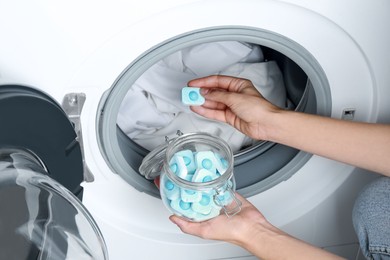 Photo of Woman putting water softener tablet into washing machine, closeup