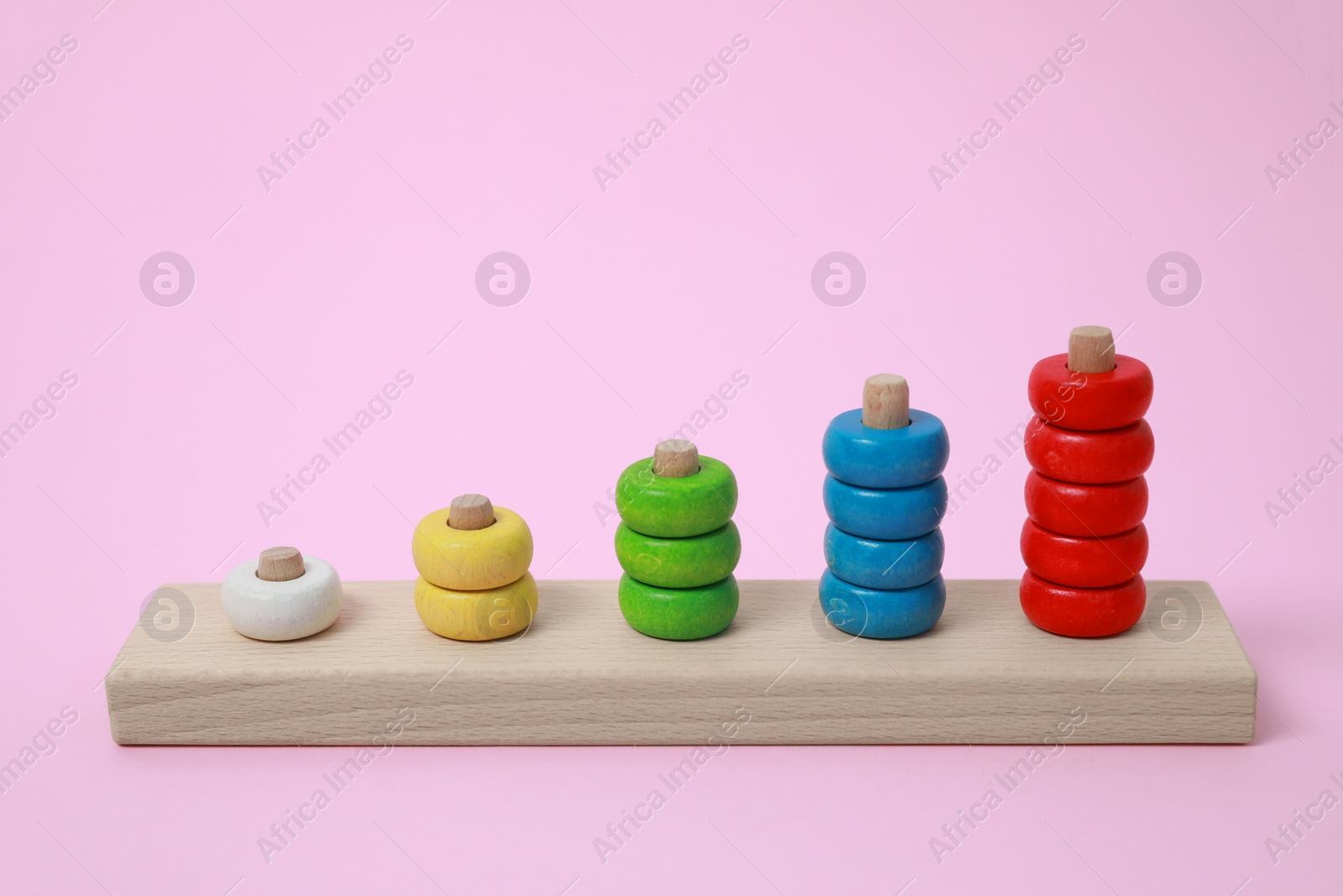 Photo of Stacking and counting game wooden pieces on pink background. Educational toy for motor skills development