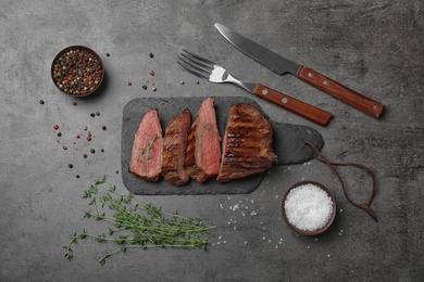 Photo of Flat lay composition with slices of grilled meat on grey table