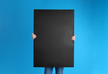 Man holding blank poster on blue background