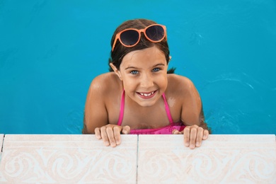 Photo of Happy cute girl with sunglasses in swimming pool