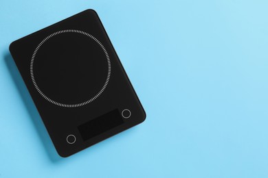 Modern digital kitchen scale on light blue background, top view. Space for text