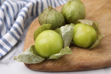 Photo of Fresh green tomatillos with husk on light table, closeup