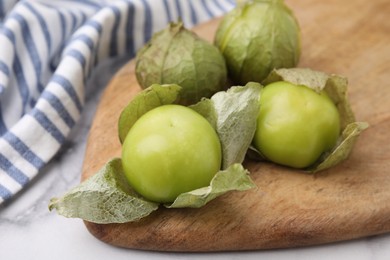 Fresh green tomatillos with husk on light table, closeup