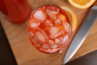 Photo of Aperol spritz cocktail and ice cubes in glass on wooden table, above view
