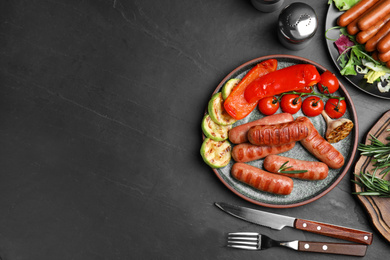 Photo of Tasty grilled sausages served on black table, flat lay. Space for text