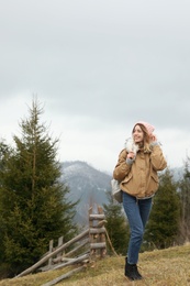 Photo of Young woman in warm clothes near conifer forest. Winter vacation