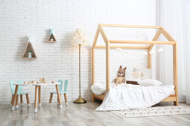 Photo of Cute children's room interior with bed and little table